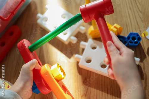 The construction bricks and tools, including hands of kid who is playing.