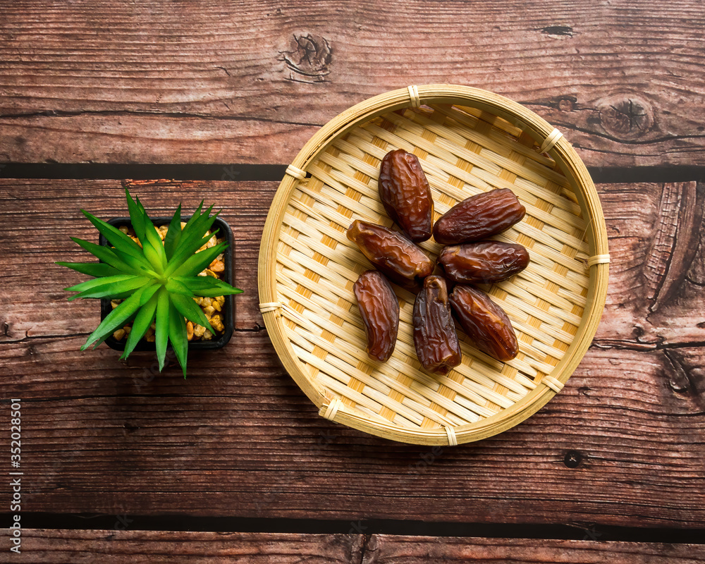 Dates or kurma on a wooden table with flower pot, the favorite food of the holy ramadhan month. Dates or kurma on a wooden table with flower pot, the favorite food of the holy ramadhan month.