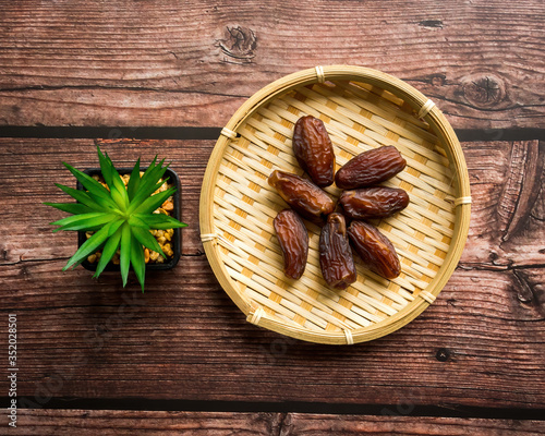 Fototapeta Naklejka Na Ścianę i Meble -  Dates or kurma on a wooden table with flower pot, the favorite food of the holy ramadhan month.