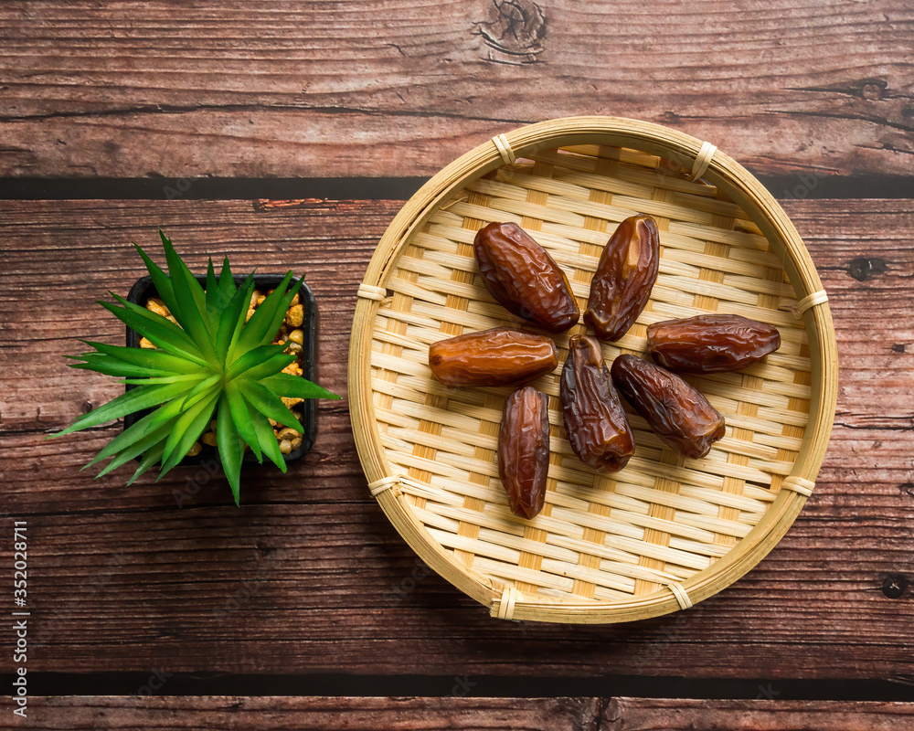 Dates or kurma on a wooden table with flower pot, the favorite food of the holy ramadhan month. Dates or kurma on a wooden table with flower pot, the favorite food of the holy ramadhan month.