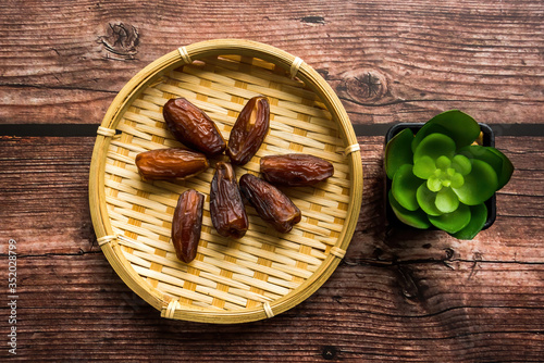 Dates or kurma on a wooden table with flower pot, the favorite food of the holy ramadhan month.