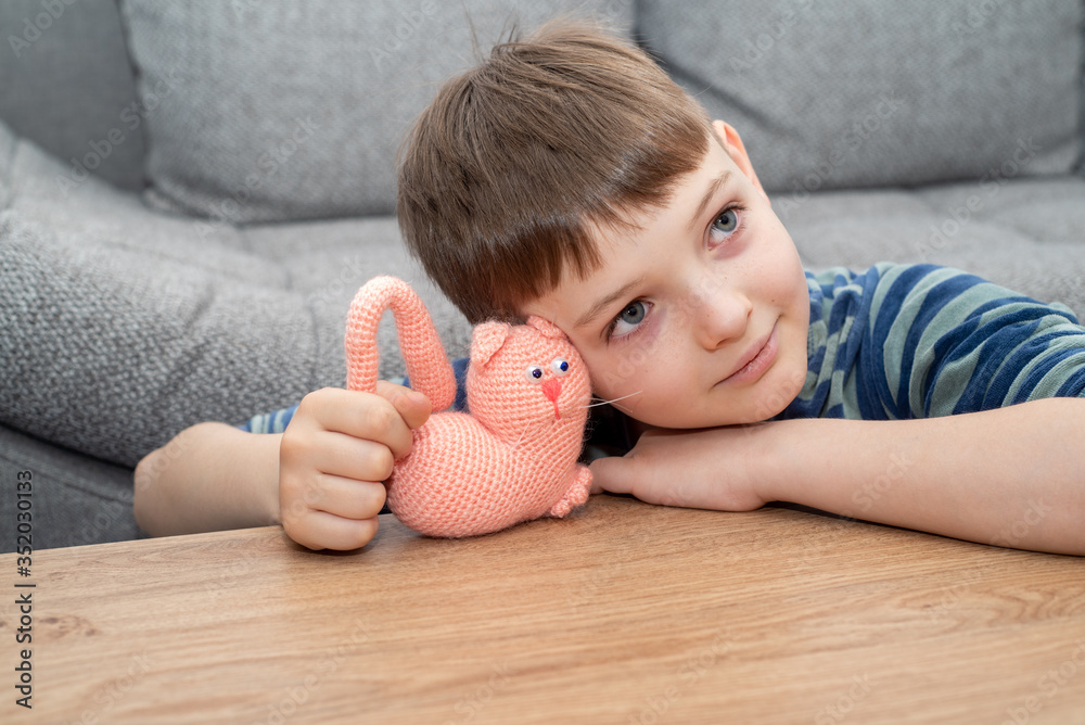 Cute child blond boy in casual clothes playing with handmade toy.