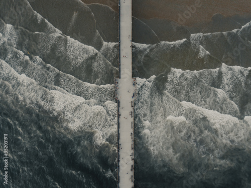 Φωτογραφία A spectacular aerial shot of a bridge going over the rushing waters of the beach