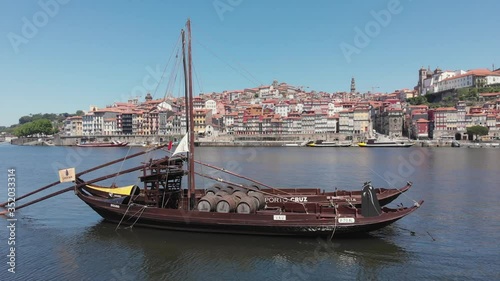 AERIAL DRONE FOOTAGE - The iconic Rabelo Boats, the traditional Port Wine transports, with the Ribeira District and the Dom Luis I Bridge over the Douro River, Porto, Portugal. Unesco World Heritage. photo