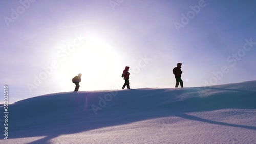 Travelers walk along top of a snowy ridge in the rays of the beautiful sun. a team of tourists strives for victory and success. business teamwork. beautiful nature of alaska, north.
