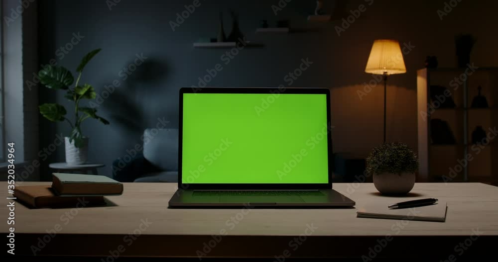 Close up shot of modern chroma key green screen laptop computer set up for work on desk at night - remote work, technology concept 4k video template