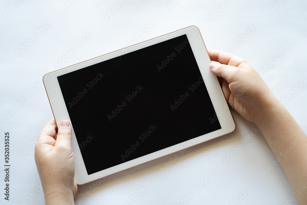 A child holds a tablet phone in his hands on a white background.