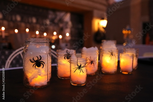 Handmade decorative Halloween mason jars filled with lights, spiders, and spider webs.