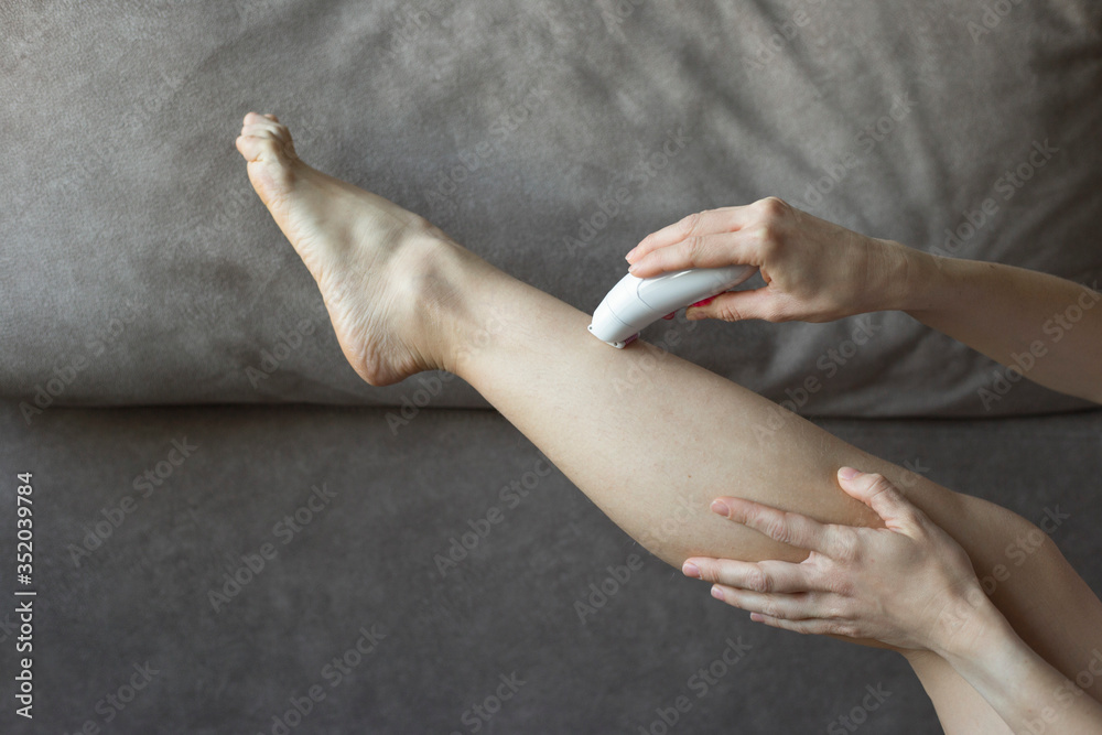 Ταπετσαρία Female hands epilate one leg with an electric epilator on a brown background