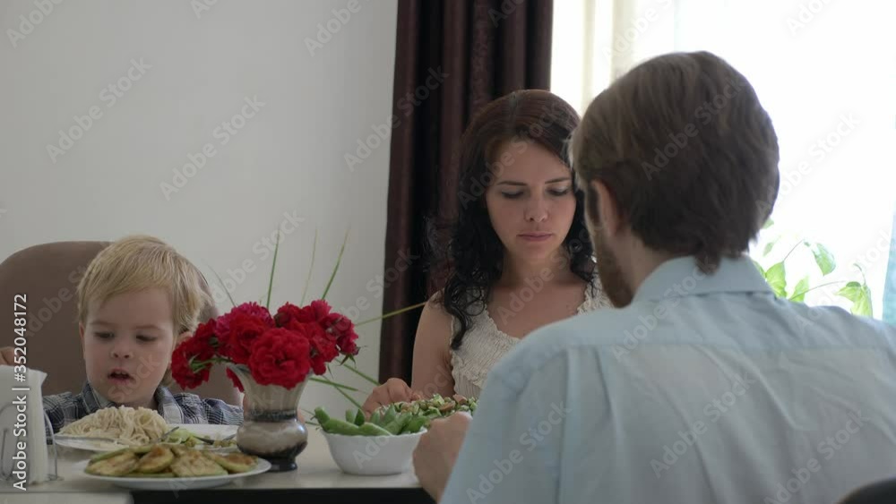 Young Happy Family is Having Dinner at Kitchen Table. Eating Tasty Healthy Food. 2x Slow motion - Half Speed 60 FPS Young Happy Family is Having Dinner at Kitchen Table. Eating Tasty Healthy Food. 2x Slow motion - Half Speed 60 FPS