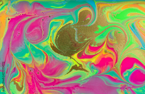Fluorescent marble pattern with golden glitter. Green and pink liquid background. Artwork abstract bright texture.