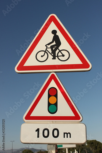 Road sign for cyclists mounted on the road. Traffic light after a hundred meters. A reminder for cyclists. Close-up.