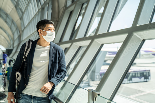 Asian traveler business man wear face mask waiting to board airplane.