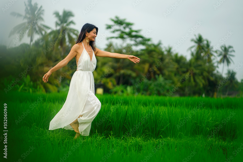 outdoors holidays portrait of middle aged attractive and elegant Asian woman in white dress enjoying beauty of nature at tropical green field playful and carefree outdoors holidays portrait of middle aged attractive and elegant Asian woman in white dress enjoying beauty of nature at tropical green field playful and carefree
