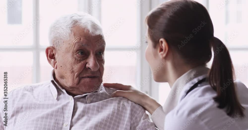 Head shot close up senior old 80s man talking to young nurse in retirement house. Professional general practitioner giving care and support to elderly mature pensioner, consulting about health indoors Head shot close up senior old 80s man talking to young nurse in retirement house. Professional general practitioner giving care and support to elderly mature pensioner, consulting about health indoors