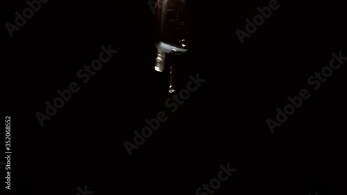 The keys to a new car sparkle in the light in the hand and fall down on a black background. Closeup. The camera moves around photo