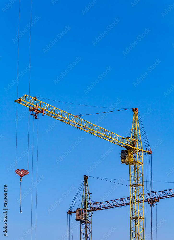 Two cranes with a light blue sky background. Construction site. Old construction equipment. Two cranes with a light blue sky background. Construction site. Old construction equipment.
