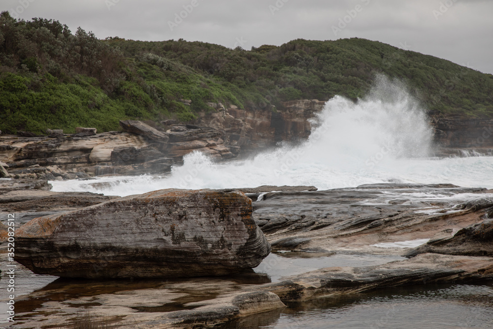 Storm in the ocean. Cloudy sky. Big waves are crashing into the rocks making white foam. Storm in the ocean. Cloudy sky. Big waves are crashing into the rocks making white foam.