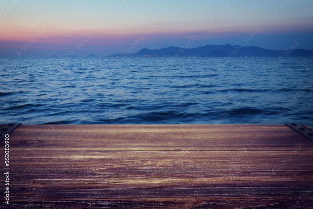 background of wood deck in front of blurred sea at sunset. ready for product display