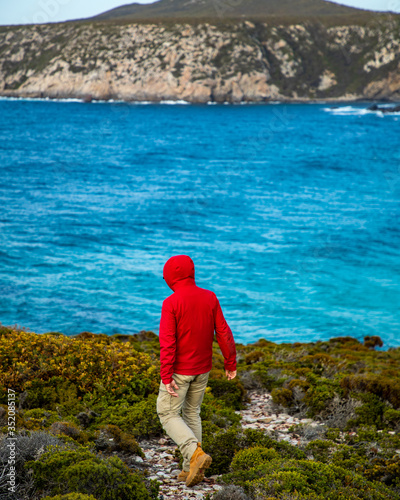 Man in red jacket walking along the beautiful coastline and exploring the cliffs of Fitzgerald River National Park, in Western Australia. The image was taken aerially from a drone.  © Sky Perth