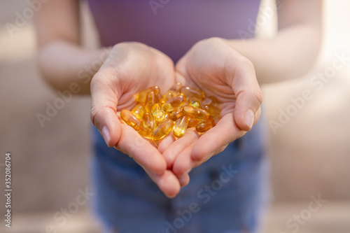 A handful of vitamin d capsules are in women's hands. Blurred background