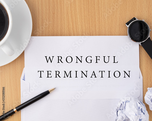 Wrongful termination document on wooden table with pen and smartwatch, termination of employment and resignation concept
