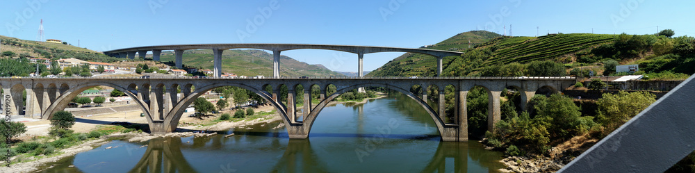 Peso da Regua, Portugal - August 2, 2016: Bridges across Douro River east of Porto in the Portuguese wine region, terraced vineyards on hillslopes in the background 