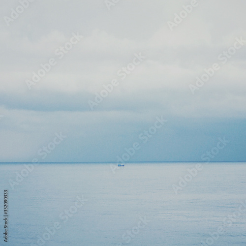 Minimal seascape. abstract of boat sailing in the sea under storm clouds on the horizon with noise and grainy style for Small boats should leave the shore and startup concept. © Goodvibes Photo