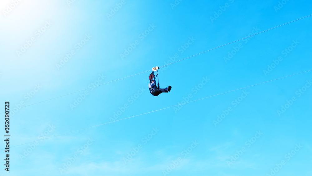 Fototapeta premium Motion blur of Extreme sportsman jumps on a rope with bright sunlight clear blue sky background.