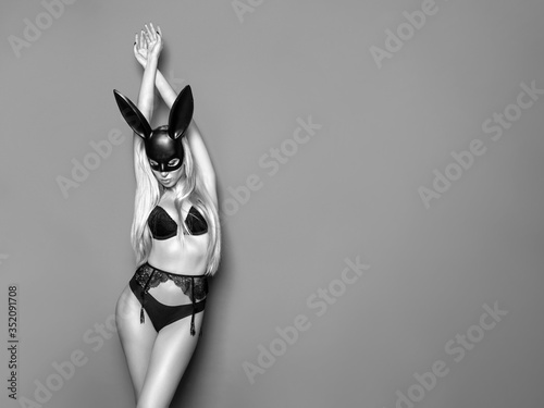 Portrait of young beautiful sexy woman with large breasts. Model wearing carnival black mask of Easter bunny rabbit.Hot blonde girl posing in studio