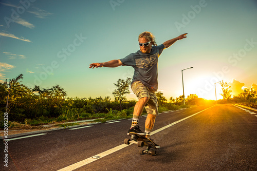 Skater rides on a highway against the backdrop of incredible sunset