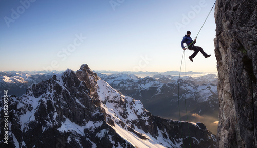 Epic Adventure Extreme Sport Composite of Rock Climbing Man Rappelling from a Cliff. Mountain Landscape Background from British Columbia, Canada.