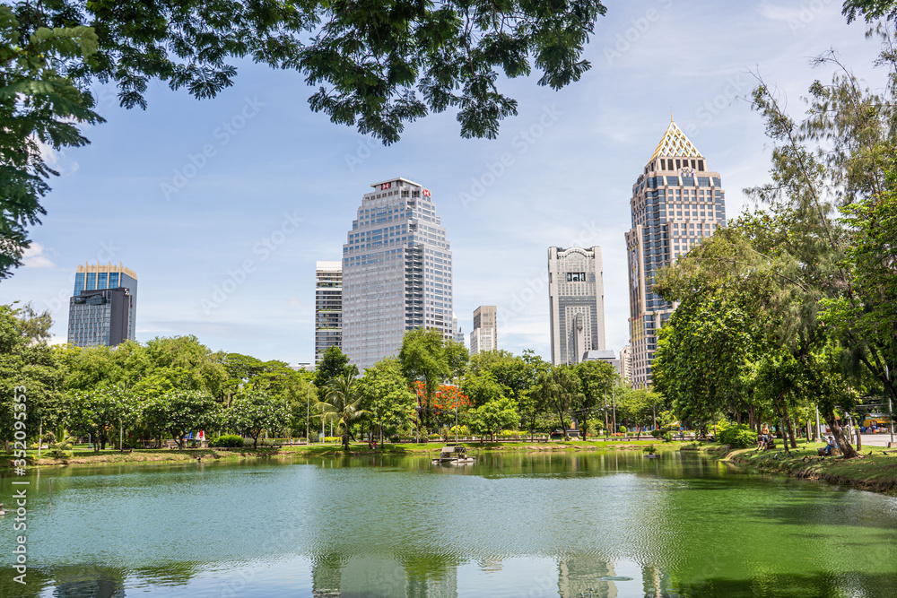 Fototapeta premium Bautiful view of lake and modern buildings in Lumpini Park, Bangkok, Thailand