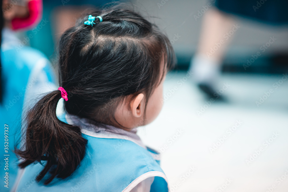 Naklejka premium The small Asian children before kindergarten in white and light blue uniform are sitting and watching fun and enjoyable story-telling activities.