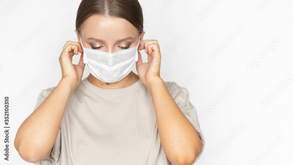 Beautiful caucasian girl in a coronavirus medical mask of a doctor shows how to dress properly. Prevention of infection during the global pandemic. Health care. Banner crop Beautiful caucasian girl in a coronavirus medical mask of a doctor shows how to dress properly. Prevention of infection during the global pandemic. Health care. Banner crop