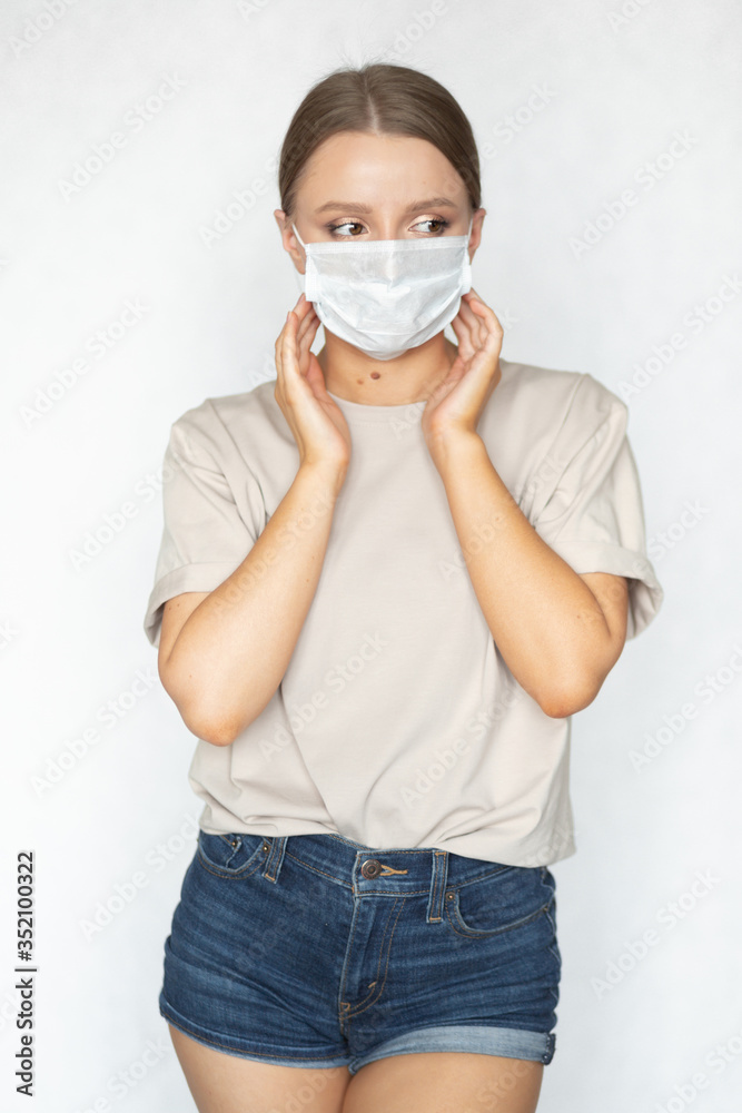 Beautiful caucasian girl in a coronavirus medical mask of a doctor posing on a white background. Prevention of infection during the global pandemic. Health care.