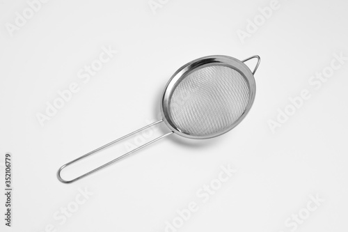 Metal sieve colander isolated on white background. Metallic strainer with handle. High-resolution photo.Front side.