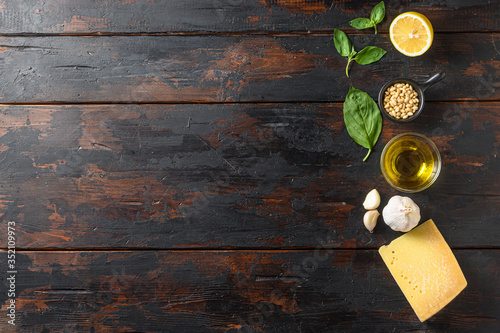 Different ingredients for pesto. . Parmesan cheese, basil leaves, pine nuts, olive oil, garlic and salt. Traditional Italian cuisine.  On the wood planks background space for text