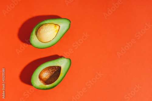 Two avocado pieces on an orange background. Flat lay. Top view. Bright picture