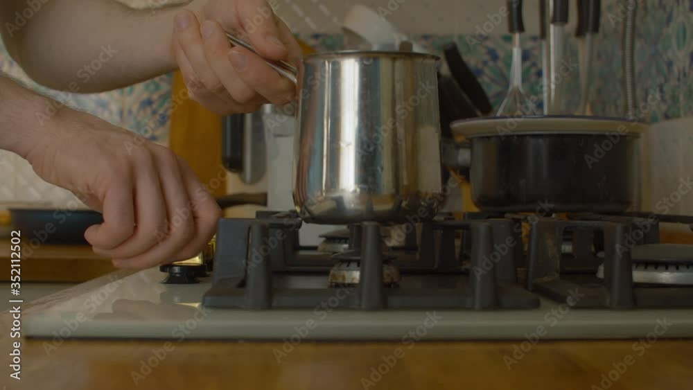 Close up male hand putting cezve on the stove and lighting a fire under it. Making turkish coffee over gas stove. Cooking of hot drinks closeup Close up male hand putting cezve on the stove and lighting a fire under it. Making turkish coffee over gas stove. Cooking of hot drinks closeup