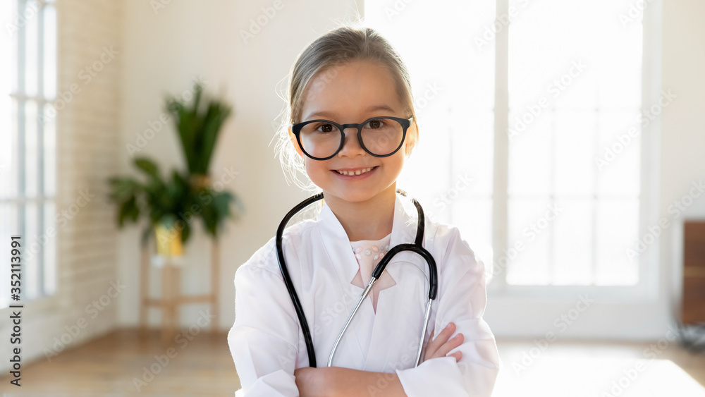 Happy cute little preschooler girl in white medical uniform and glasses act like doctor, portrait of smiling small child in whites have fun playing in hospital, engaged in funny game, career concept Happy cute little preschooler girl in white medical uniform and glasses act like doctor, portrait of smiling small child in whites have fun playing in hospital, engaged in funny game, career concept
