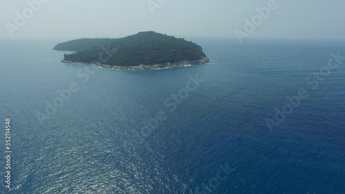 Aerial shot of island amidst beautiful ocean, drone is flying forward over sea - Dubrovnik, Croatia photo