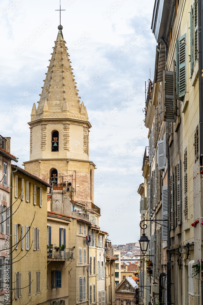 A typical street at Le Panier quarter in Marseille with the bell tower of the church of Notre Dame des Accoules, France