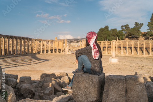 A woman traveller sitting on rock looking at Roman column in Jerash Roman ruin and ancient city in Jordan