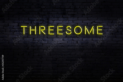 Photos Night view of neon sign on brick wall with inscription threesome