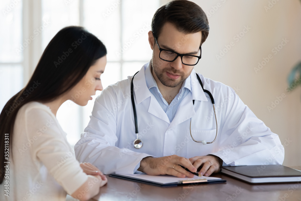 Man physician in white medical uniform explain healthcare insurance program on medical card to client, male doctor or GP talk consult woman patient about prescription or illness checkup results Man physician in white medical uniform explain healthcare insurance program on medical card to client, male doctor or GP talk consult woman patient about prescription or illness checkup results