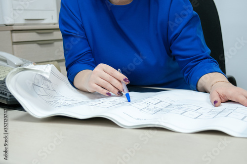 Office, a woman in a blue dress working with drawings at the table