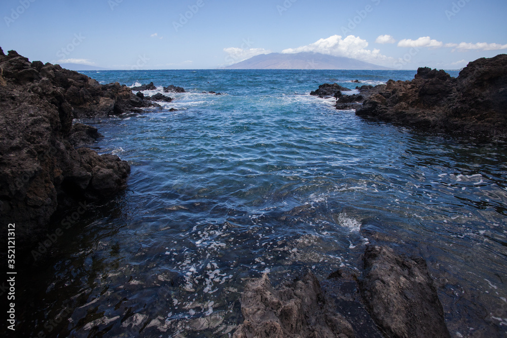 Rocky Channel that leads out to the ocean with an island in the distance in Hawaii