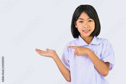 Asian Little school girl showing something over her hand and finger pointing ,child looking smile to camera isolated in white background for show or display advertising