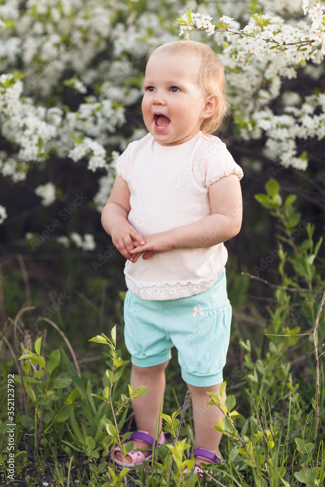 Cute baby girl on a background of white blossoms of an apple tree Cute baby girl on a background of white blossoms of an apple tree